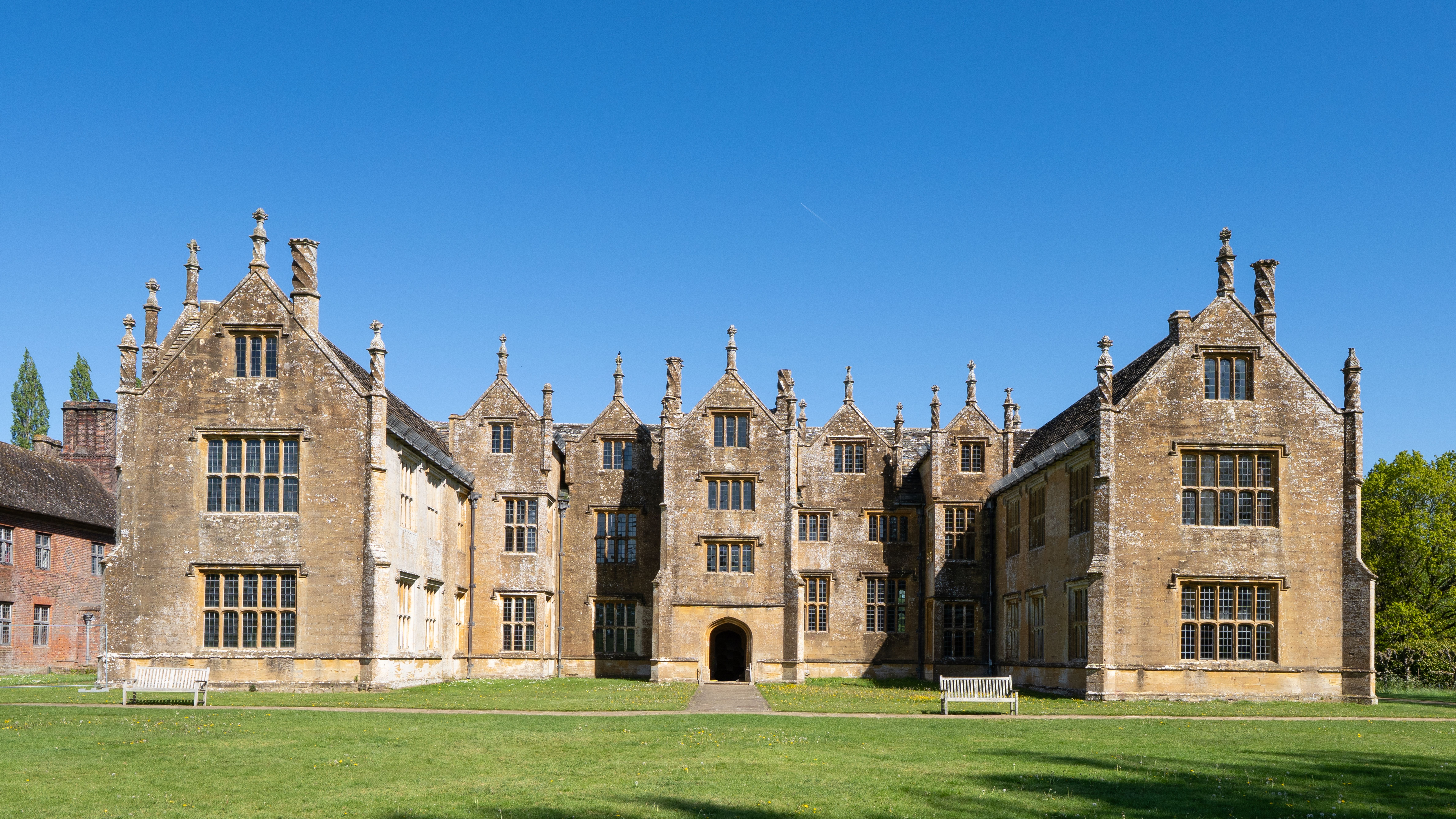 A beautiful historic English manor set against a clear blue sky, showcasing classic architecture.
